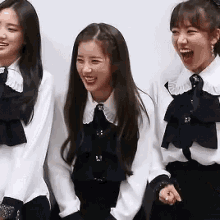 three women are standing next to each other laughing and smiling .