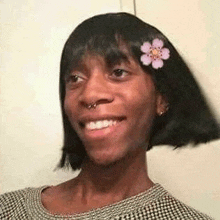 a woman with a flower in her hair is smiling and looking at the camera .