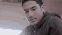 a close up of a man 's face with a beard wearing a hoodie .