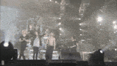 a group of people standing on a stage with the letter d on the bottom right