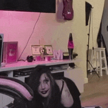 a woman is sitting on a chair in a living room with a pink light behind her .