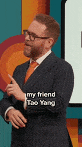 a man in a suit and tie is standing in front of a colorful background and pointing at something .