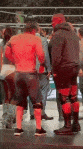 a man without a shirt is standing in a wrestling ring with other men