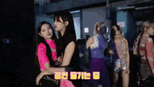 a group of girls are hugging each other in a dark room with korean writing on the bottom right