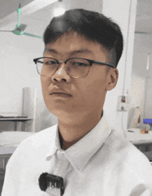 a young man wearing glasses and a white shirt has a badge that says ' i.i. ' on it