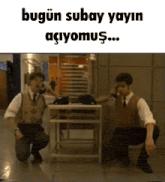 two men are kneeling down in front of a table and talking on a phone .