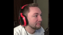 a man with a beard is wearing red headphones and making a face .