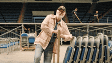 a man with a beard is standing next to folding chairs