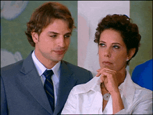 a man in a suit and tie and a woman in a white shirt are looking at each other
