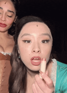 a woman is putting lipstick on another woman 's lips