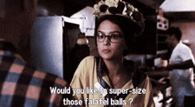 a woman wearing glasses and a crown says " would you like to super size those falafel balls " .