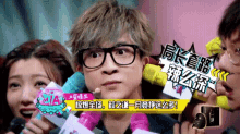 a man wearing glasses is being interviewed by a group of people holding microphones