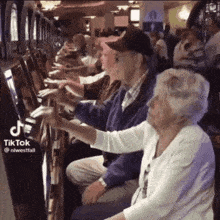 a couple of elderly people playing a slot machine with tiktok written on the bottom right