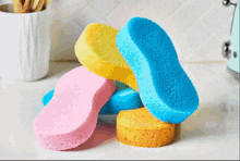 four different colored sponges are stacked on top of each other on a counter
