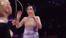 a woman wearing headphones is dancing on a stage in front of a rai hd sign