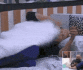 a man is laying in a bed with a pillow on his head and a picture of a man holding a pillow .