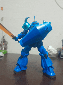 a blue robot with a sword and shield standing on a table