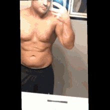a shirtless man is taking a picture of himself in the mirror