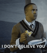 a man in a sweater and tie is holding a plate of food and eating a piece of cheese .