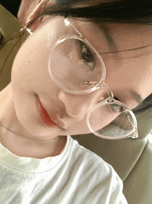 a woman wearing glasses and a white shirt looks at the camera