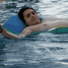 a shirtless man is floating on a raft in a swimming pool