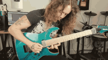 a man with long hair is playing a turquoise ibanez guitar