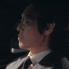 a man wearing glasses and a suit is looking down