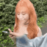 a woman with long red hair is looking at her phone .
