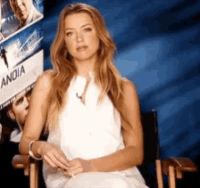 a woman sits in a chair in front of a sign that says ania