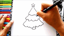 a person is drawing a christmas tree with markers