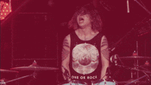 a man wearing a one ok rock tank top plays drums
