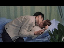 a man and a woman are kissing on a bed in a room .