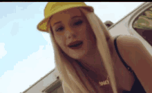 a blonde woman wearing a yellow hat and a necklace that says ' smack ' on it