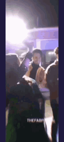 a group of people are standing in a dark room in front of a car .