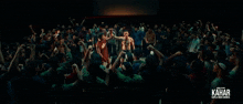 a crowd of people are gathered in a dark room with kahar written on the bottom