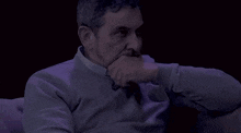 a man in a purple sweater has a sticker on his collar that says ' a '