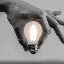 a hand is holding a light bulb with a flame coming out of it