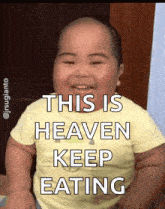 a baby is smiling with the words " this is heaven keep eating " above him