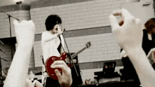 a man is playing a guitar and singing into a microphone while a crowd cheers .