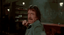 a man with a beard is making a funny face while holding his fist up in the air .