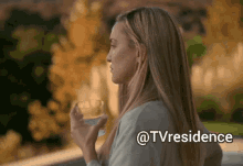 a woman holding a glass of water with the words @tvresidence written below her