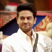 a man in a white jacket is smiling with a black strap around his shoulder