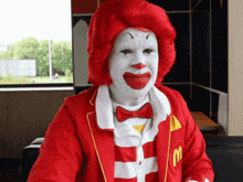 a man dressed as mcdonald 's ronald mcdonald with red hair and white face paint