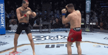 two men are fighting in a ring with a bud light banner behind them