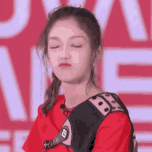 a woman wearing a red shirt and a black vest is making a funny face .