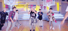 a group of young men are dancing on a basketball court with the number 12 on the wall behind them