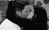 a man and a woman kissing in a black and white photo .