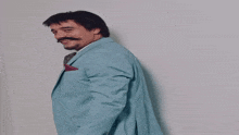 a man with a beard and mustache wears a light blue suit