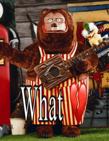 a stuffed bear holding a guitar with the word what on the bottom right