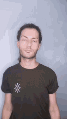 a man with a beard wearing a black shirt with a cross on it